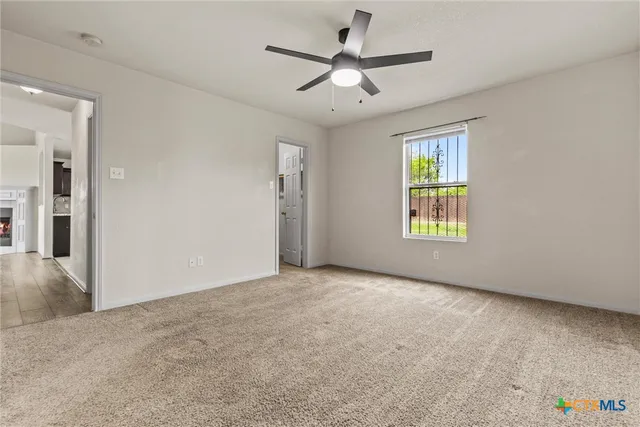 an empty room with windows and ceiling fan
