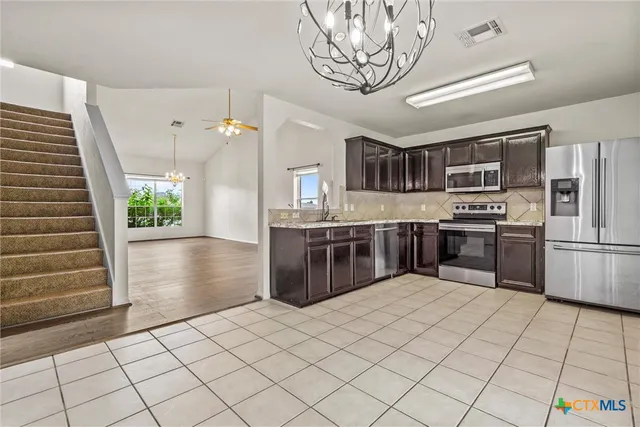 a kitchen with stainless steel appliances granite countertop a stove a sink dishwasher and a refrigerator