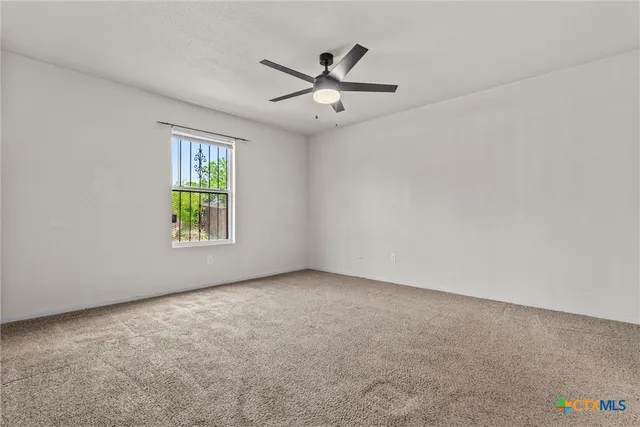 an empty room with window and ceiling fan