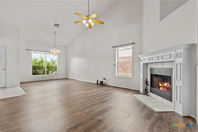 an empty room with windows fireplace and wooden floor