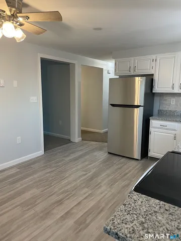 a view of a kitchen with a refrigerator a ceiling fan and wooden floor