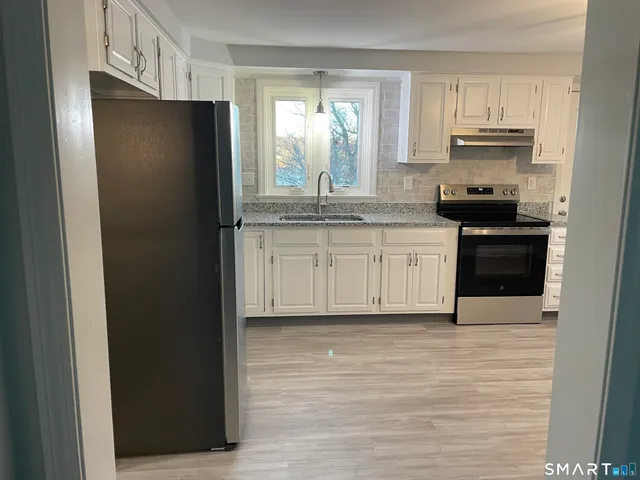 a kitchen with granite countertop a refrigerator stove and sink