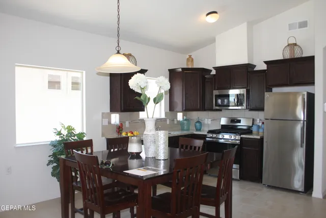 a kitchen with stainless steel appliances a dining table chairs and refrigerator