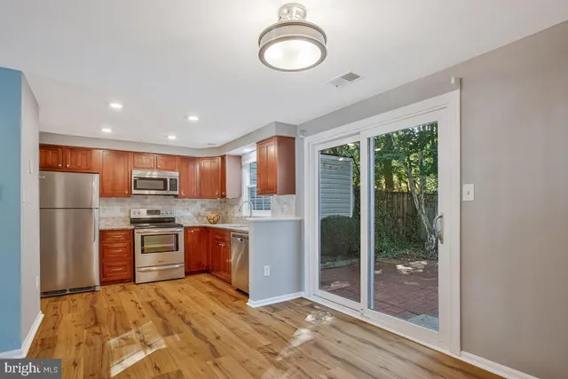 a large kitchen with kitchen island a large counter top space a sink stainless steel appliances and cabinets