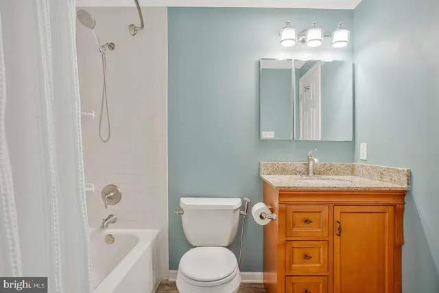 a bathroom with a granite countertop toilet a sink and mirror