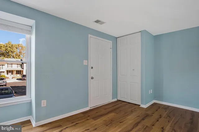 a view of an empty room with wooden floor and a window