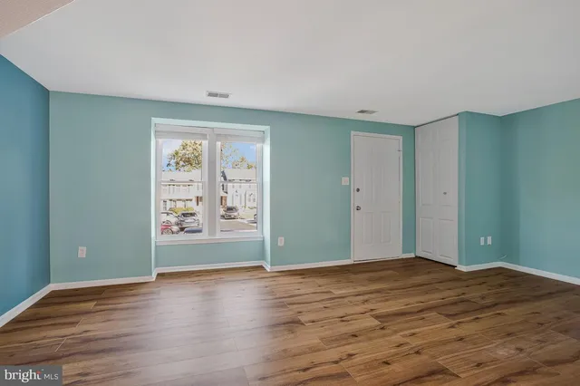 a view of an empty room with window and wooden floor