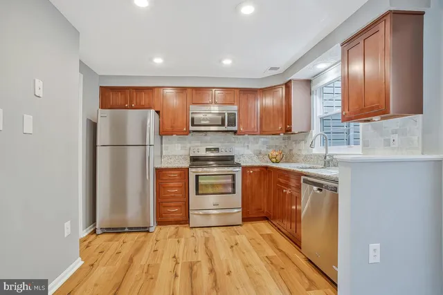 a kitchen with granite countertop a refrigerator stove top oven and sink