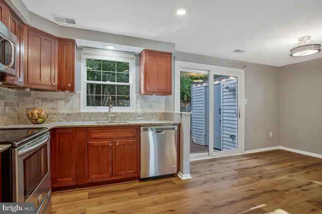 an open kitchen with granite countertop wooden cabinets a sink and a stove with wooden floor