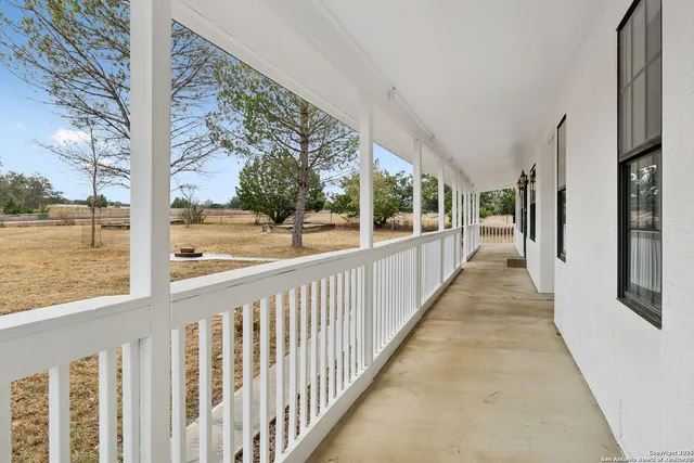 a kitchen with granite countertop a stove a sink and white cabinets with wooden floor