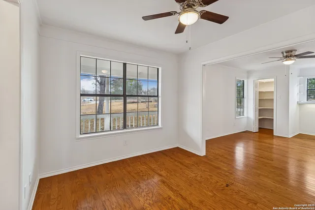 an empty room with windows and fan