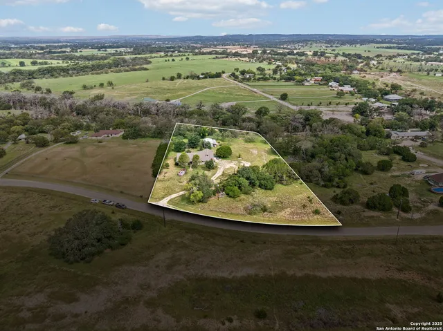 a view of an empty room with wooden floor fireplace and a window