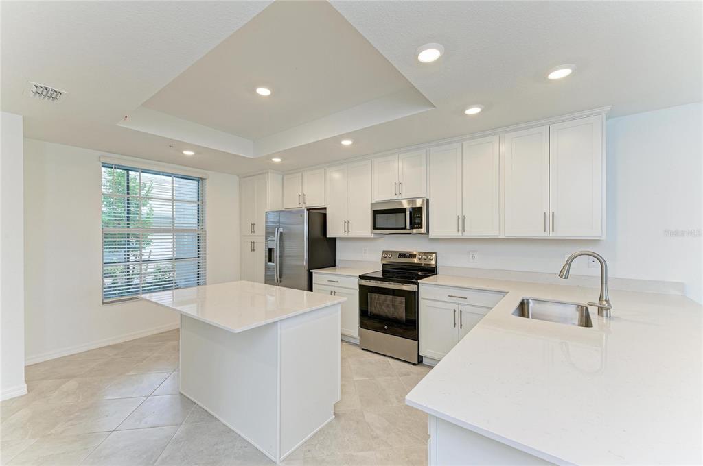 19015 Scallop Loop, Unit 7118 Lakewood Ranch, FL 34211 - Photo 14 of 48 a large kitchen with stainless steel appliances granite countertop a sink a stove a refrigerator cabinets and living room view