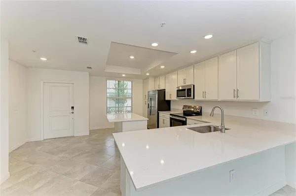 a large white kitchen with a sink a large mirror and a refrigerator