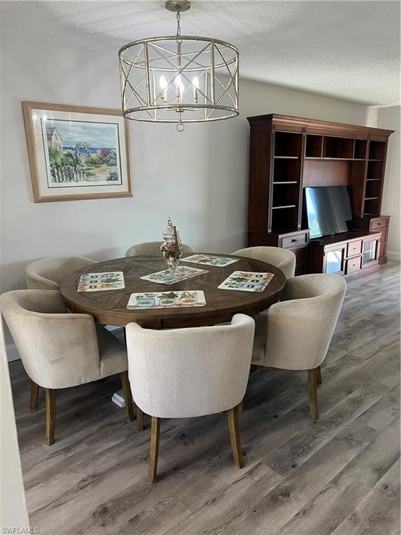 4346 27th Court Southwest, Unit 102 Naples, FL 34116 - Photo 10 of 15 a view of a dining room with furniture wooden floor and chandelier