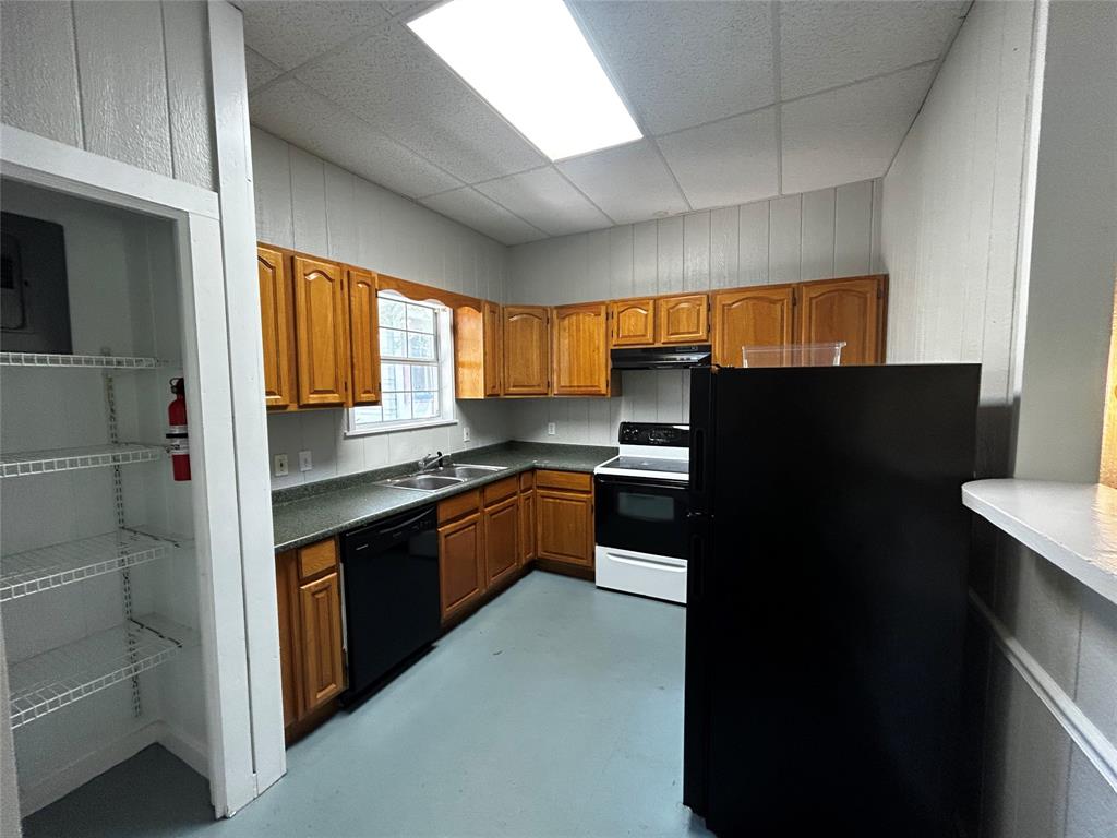 903 West 30th Street, Unit B Austin, TX 78705 - Photo 2 of 9 Kitchen with wood finish cabinetry, black appliances, a drop ceiling, dark countertops, and concrete flooring