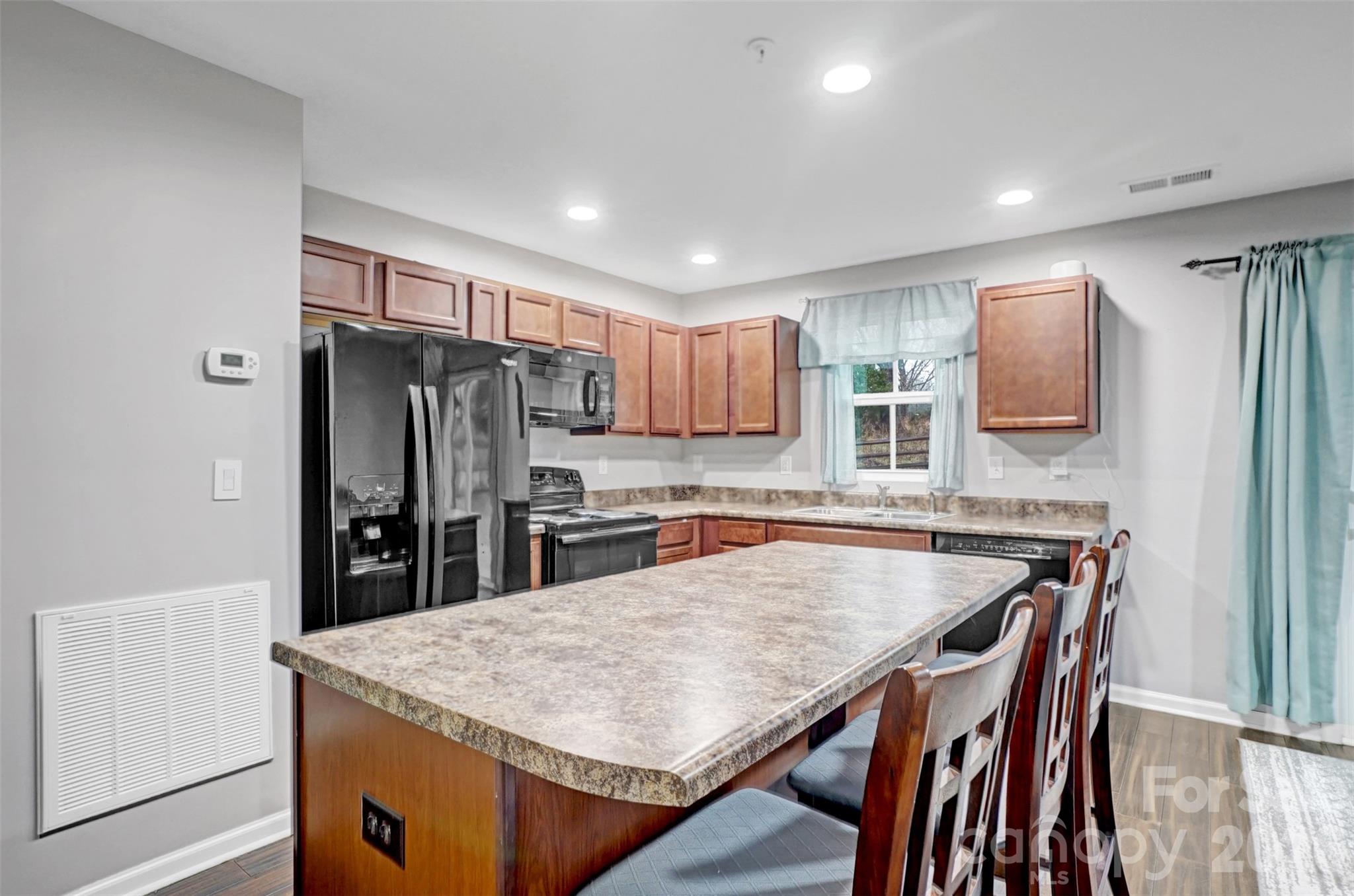 1144 Tangle Ridge Drive Southeast Concord, NC 28025 - Photo 12 of 27 a kitchen with stainless steel appliances granite countertop a table chairs sink refrigerator and microwave