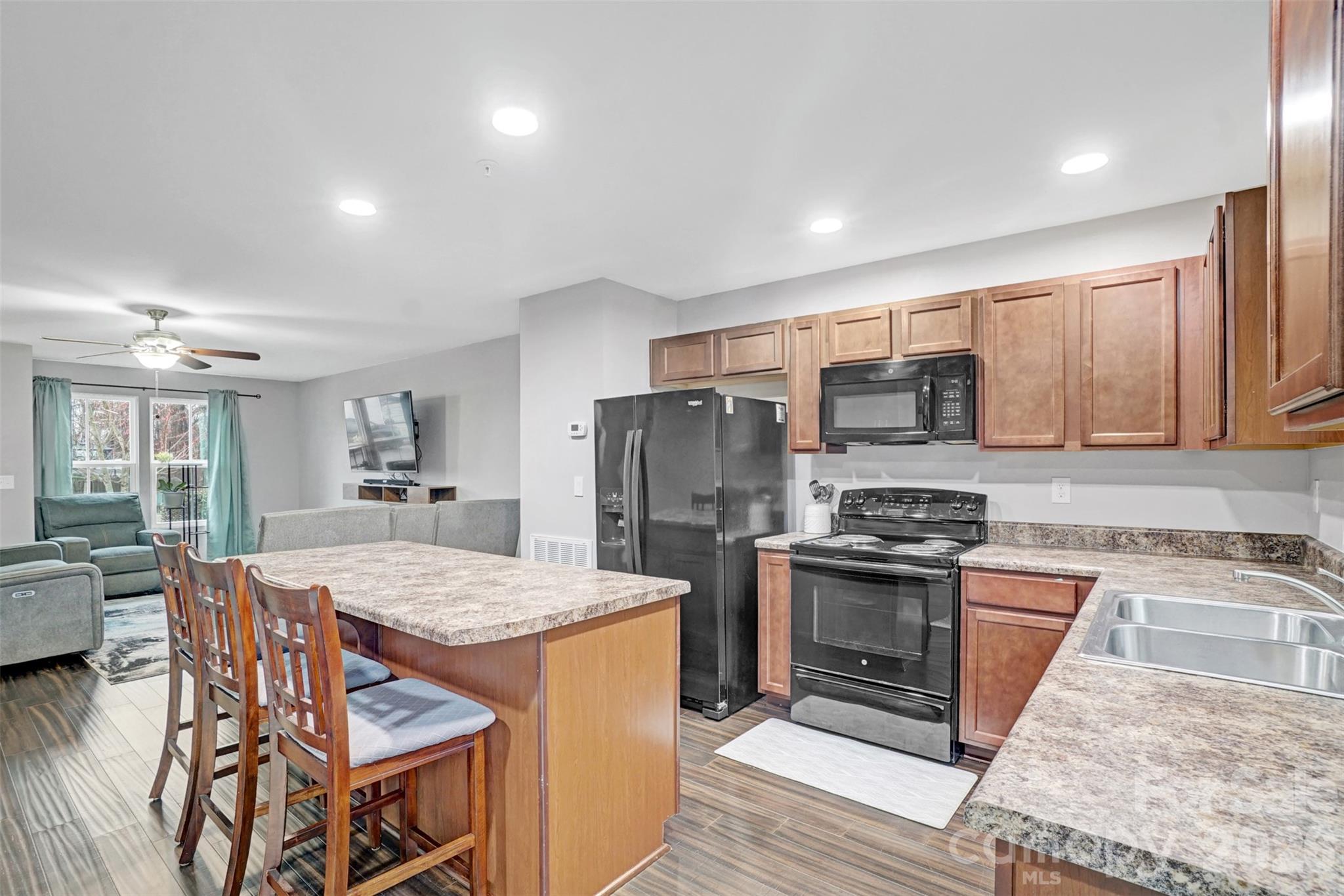 1144 Tangle Ridge Drive Southeast Concord, NC 28025 - Photo 13 of 27 a kitchen with stainless steel appliances granite countertop a stove top oven a sink dishwasher a dining table and chairs with wooden floor