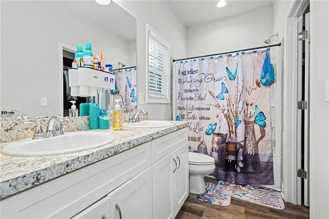 a bathroom with a granite countertop sink a toilet a shower curtain and a bath tub