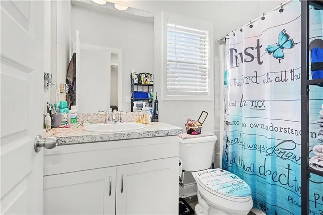 a bathroom with a granite countertop toilet sink and mirror