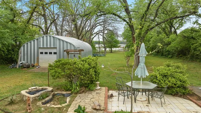 a view of a big yard with table and chairs potted plants and large tree