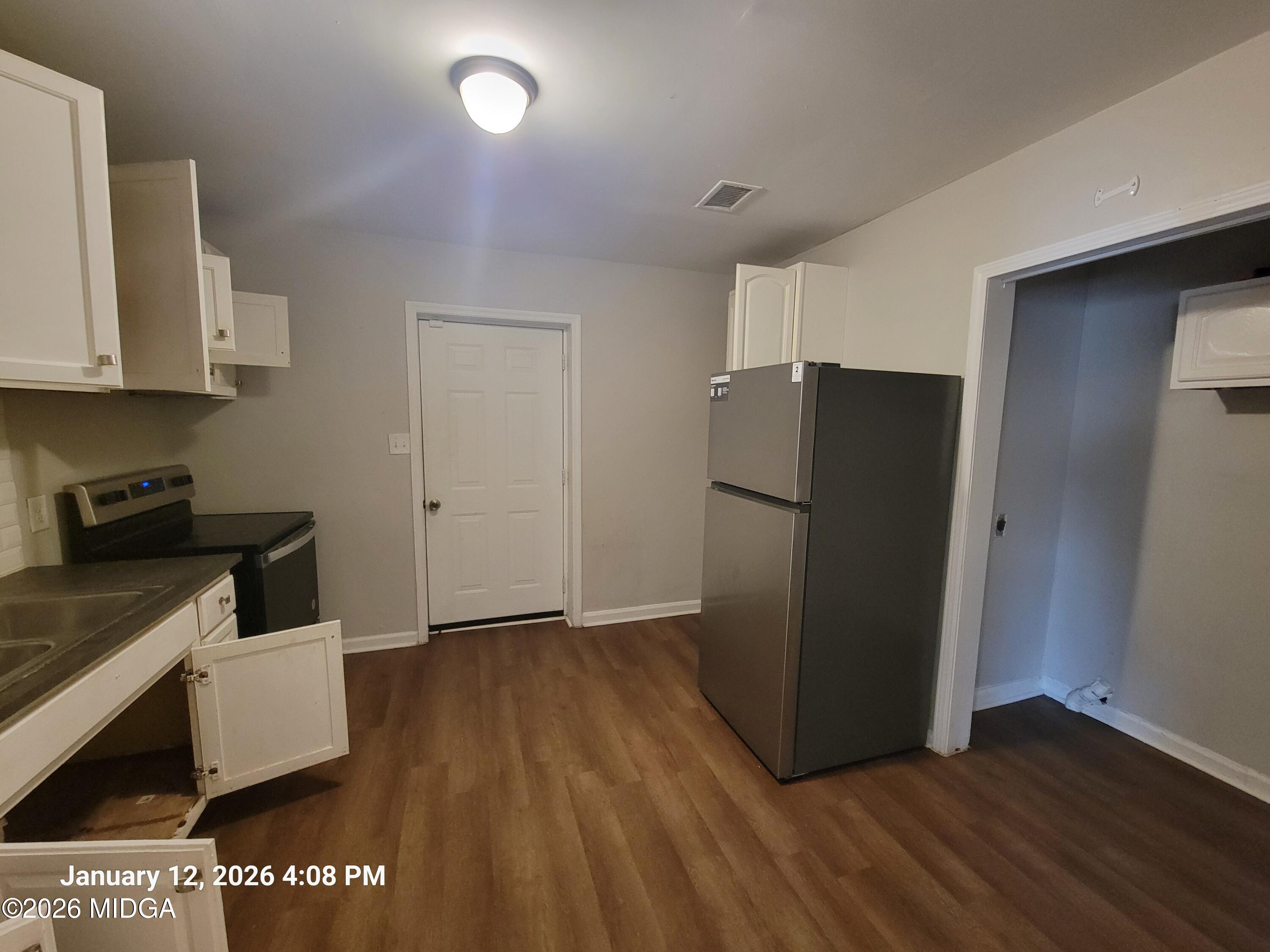 2872 Antioch Road Macon, GA 31206 - Photo 9 of 12 a view of a refrigerator in kitchen and an empty room with wooden floor
