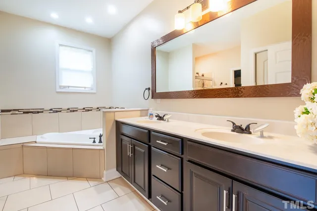 a bathroom with a tub a sink and mirror