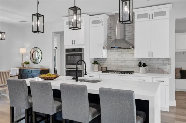 a kitchen with stainless steel appliances kitchen island granite countertop a table chairs and a stove