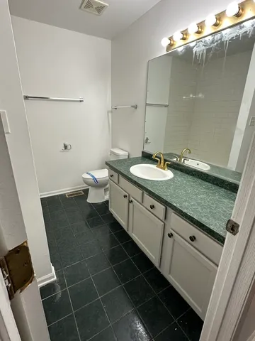 a bathroom with a granite countertop sink a toilet and a mirror