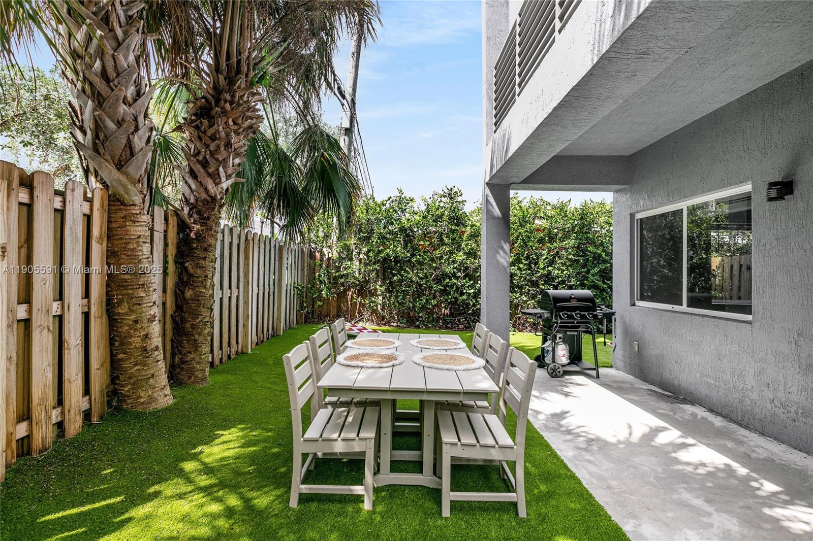 1123 Northeast 23rd Terrace Pompano Beach, FL 33062 - Photo 28 of 35 a backyard of a house with table and chairs floor to ceiling window with garden