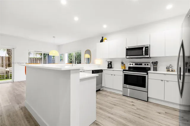 a kitchen with white cabinets and appliances