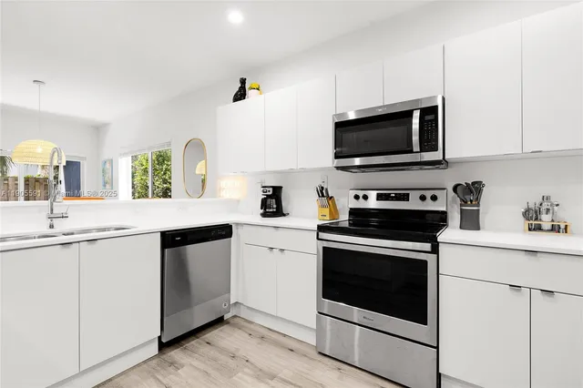 a kitchen with cabinets stainless steel appliances a sink and a stove