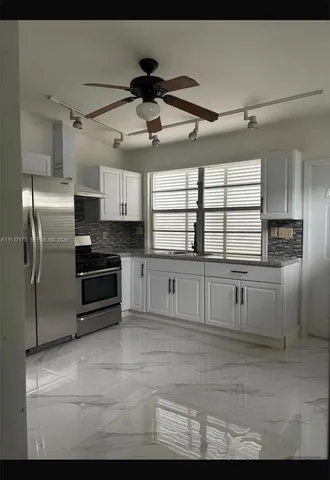 a kitchen with granite countertop a refrigerator and cabinets