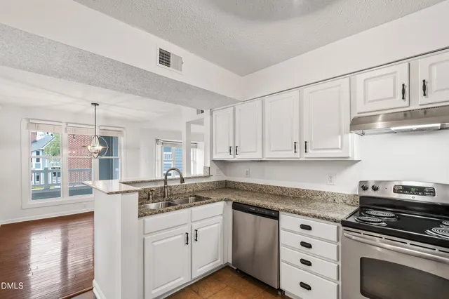 a kitchen with granite countertop a sink cabinets stainless steel appliances and a window