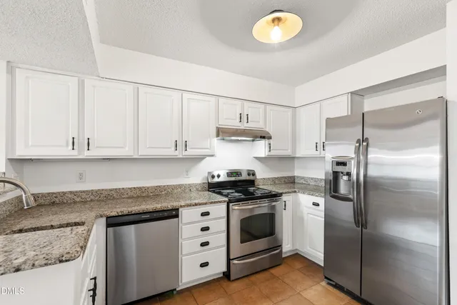 a kitchen with stainless steel appliances granite countertop a sink a stove and a refrigerator