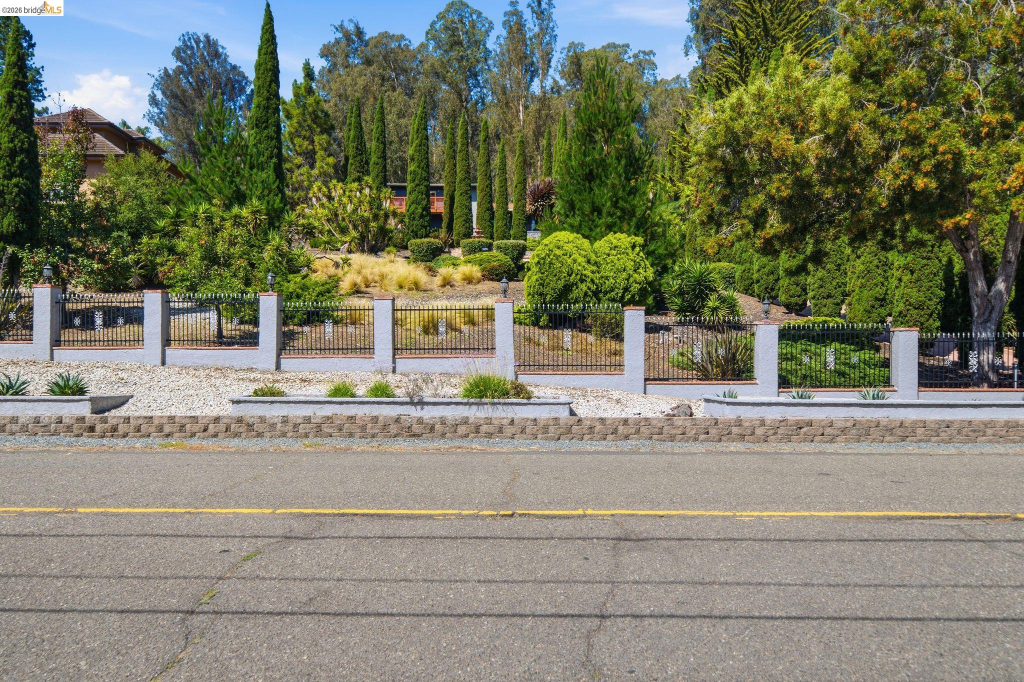 11133 Golf Links Road Oakland, CA 94605 - Photo 3 of 57 Street-level view featuring a decorative perimeter fence with stone pillars and black wrought iron sections