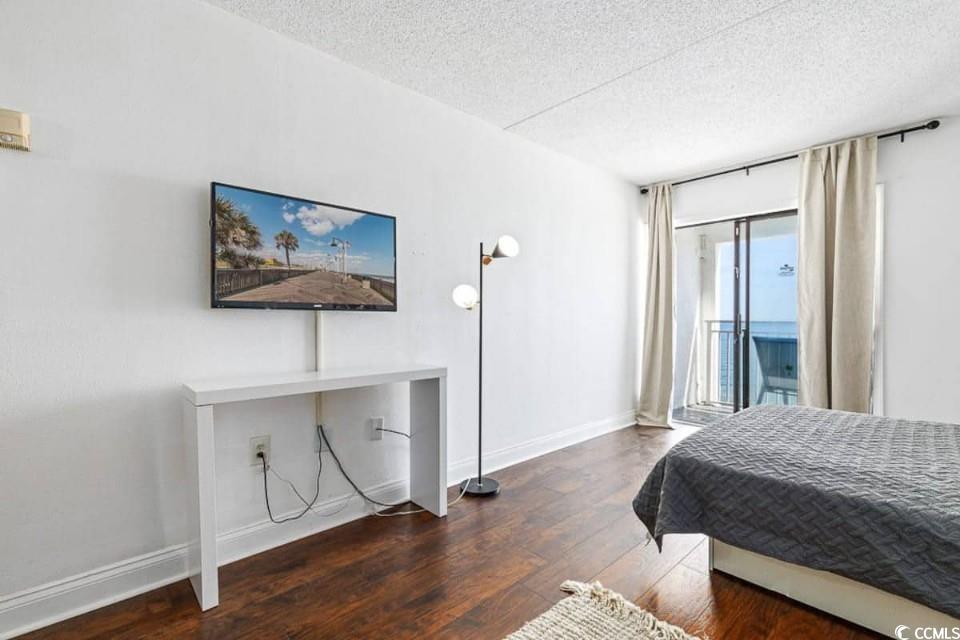 1207 South Ocean Boulevard, Unit 21001 Myrtle Beach, SC 29577 - Photo 12 of 23 Bedroom featuring access to outside, dark wood-style floors, and a textured ceiling
