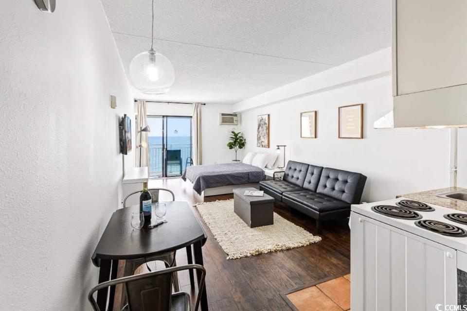 1207 South Ocean Boulevard, Unit 21001 Myrtle Beach, SC 29577 - Photo 13 of 23 Living room featuring a textured ceiling, dark wood-style floors, expansive windows, and an AC wall unit