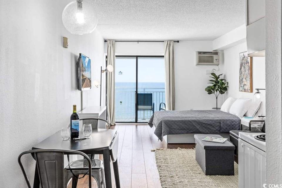 1207 South Ocean Boulevard, Unit 21001 Myrtle Beach, SC 29577 - Photo 3 of 23 Bedroom with light wood-style flooring, a textured ceiling, access to outside, a wall mounted AC, and a textured wall