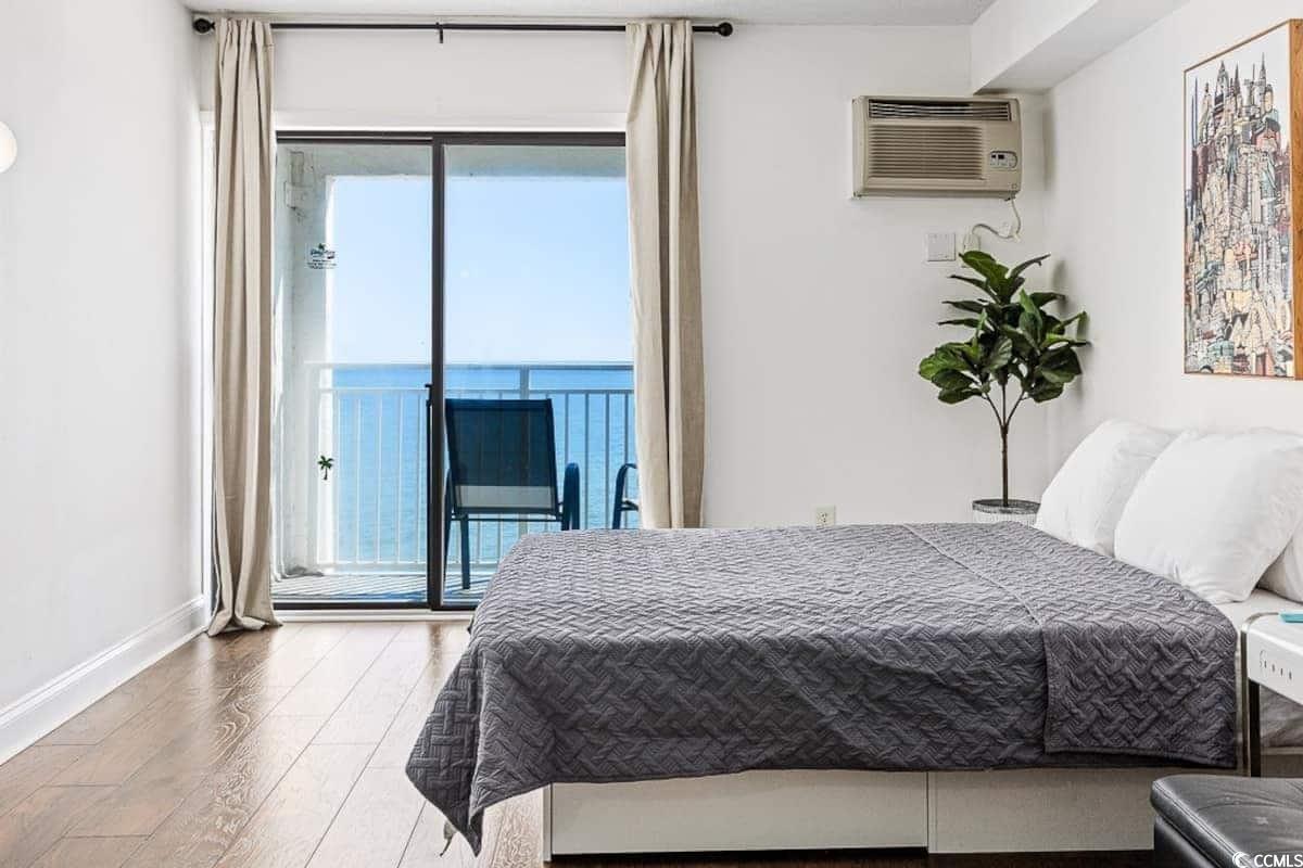 1207 South Ocean Boulevard, Unit 21001 Myrtle Beach, SC 29577 - Photo 4 of 23 Bedroom featuring wood finished floors, a water view, access to outside, and a wall unit AC