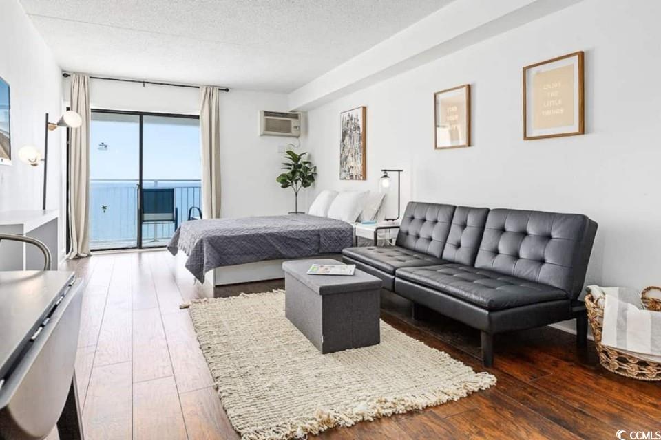 1207 South Ocean Boulevard, Unit 21001 Myrtle Beach, SC 29577 - Photo 5 of 23 Bedroom featuring access to outside, a textured ceiling, hardwood / wood-style flooring, and a wall mounted AC
