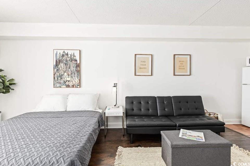 1207 South Ocean Boulevard, Unit 21001 Myrtle Beach, SC 29577 - Photo 10 of 23 Bedroom with wood finished floors, freestanding refrigerator, and a textured ceiling