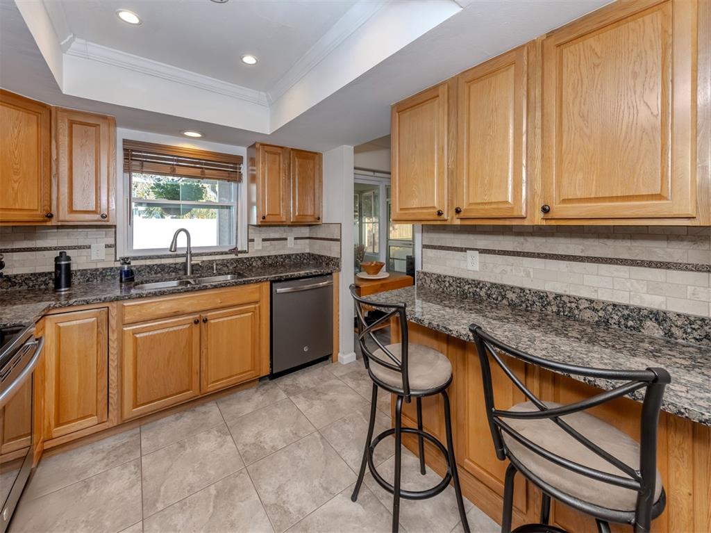 1316 Poplar Avenue Venice, FL 34285 - Photo 13 of 60 a kitchen with stainless steel appliances granite countertop wooden cabinets a sink a stove a dining table and chairs