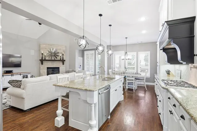 a large kitchen with kitchen island a stove a sink a dining table and chairs