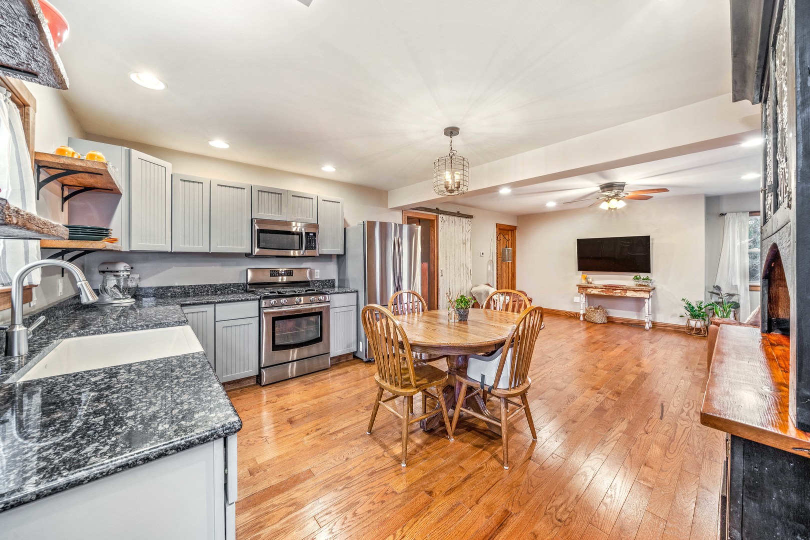 11036 Chicago Road Waterman, IL 60556 - Photo 3 of 43 a kitchen with stainless steel appliances granite countertop a stove top oven a sink a dining table and chairs with wooden floor