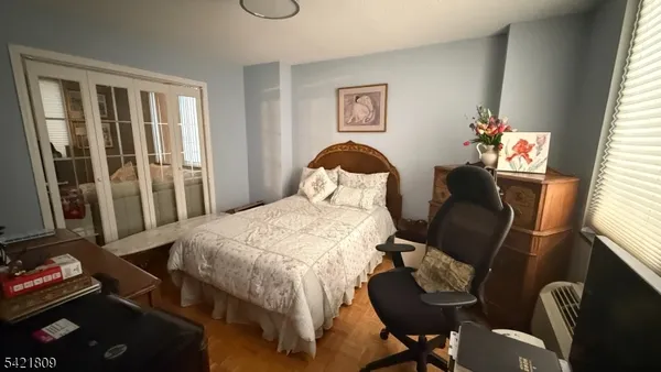 a bedroom with a bed and dresser with wooden floor