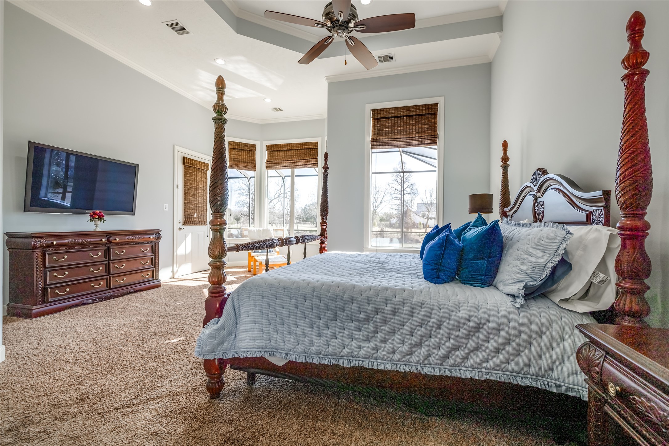 31102 Lower Oxbow Trace Fulshear, TX 77441 - Photo 19 of 50 Fabulous Primary Suite with room for a super king bed & sitting area, wall of window with lots of natural light, door out to the pool & Oxbow Lake. Rattan Blinds, carpet.