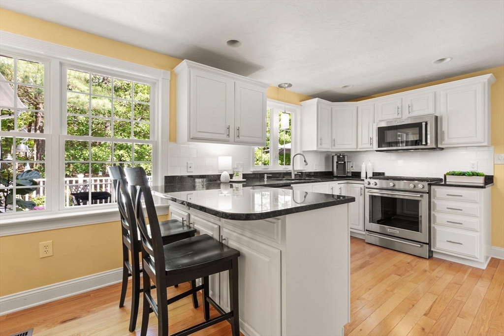 67 Bridle Path Franklin, MA 02038 - Photo 7 of 35 a kitchen with a stove a sink a microwave a dining table and chairs