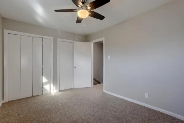 a view of an empty room and chandelier fan
