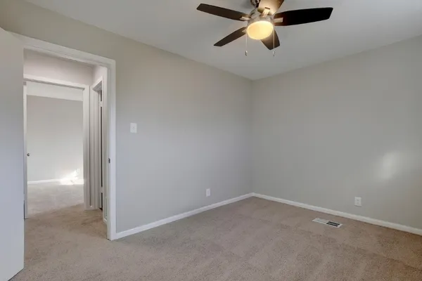 an empty room with chandelier fan and windows